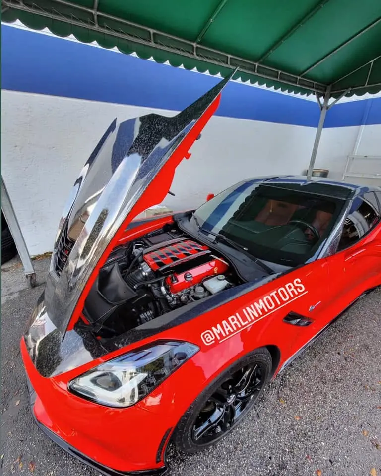 Red Chevrolet Corvette Stingray with the hood raised, showing the engine bay, at Marlin Motors in Cutler Bay, FL